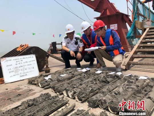 圖為勘察設(shè)計人員與海事局工作人員查看巖芯情況?！∥赫?攝