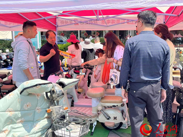 某電動(dòng)自行車品牌工作人員向消費(fèi)者介紹以舊換新相關(guān)情況。人民網(wǎng)記者 杜燕飛攝