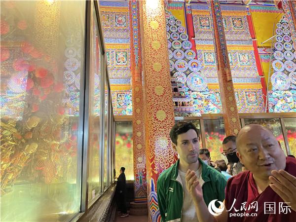 7月25日，省級(jí)非物質(zhì)文化遺產(chǎn)項(xiàng)目塔爾寺酥油花的代表性傳承人朋措堅(jiān)參（右）在塔爾寺酥油花館講解酥油花的制作過(guò)程。人民網(wǎng) 謝瑩攝