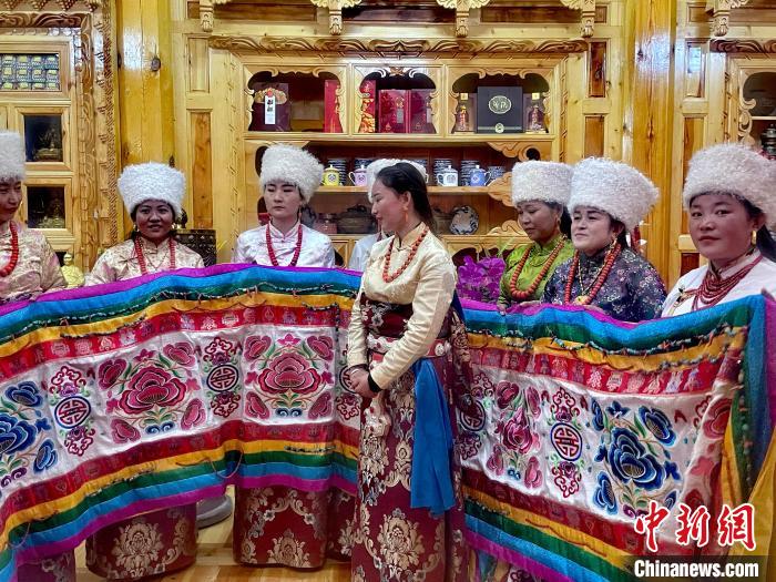圖為女性展示村民自發(fā)繡制的“百米五彩哈達”?！±钣穹?攝