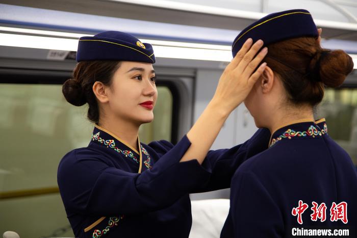 圖為青藏鐵路西格段“復(fù)興號”動車組乘務(wù)員互相整理新制服?！±罾?攝