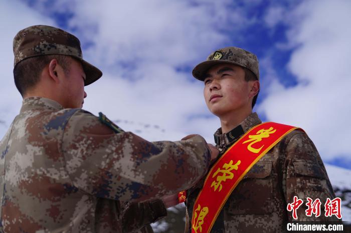 排長王朝偉(圖左)給退伍老兵佩戴大紅花?！∥鞑厣侥宪姺謪^(qū)某團(tuán)供圖